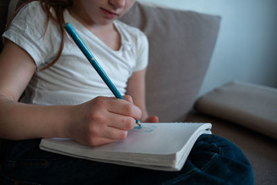 Midsection of woman reading book at home