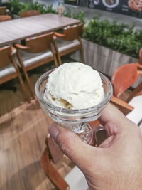 Cropped hand of person holding ice cream on table