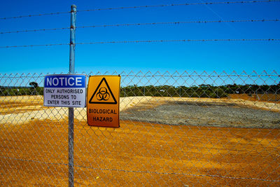 Information sign on fence against blue sky