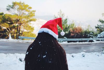 Rear view of woman on snow covered landscape against sky