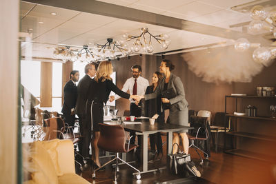 Male and female coworkers greeting in meeting room at law office