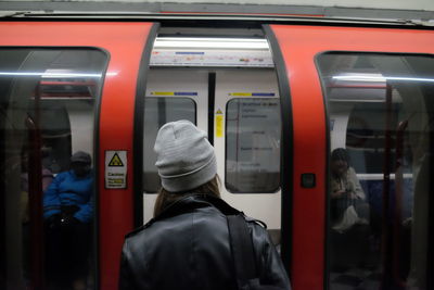 Rear view of woman standing against metro train at subway station