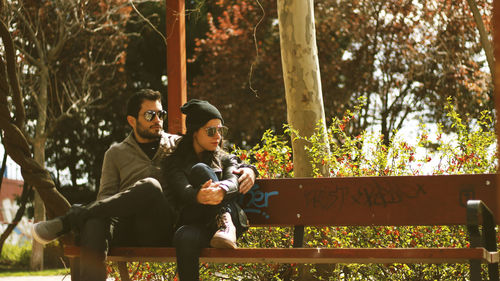 Young couple kissing on plants against trees