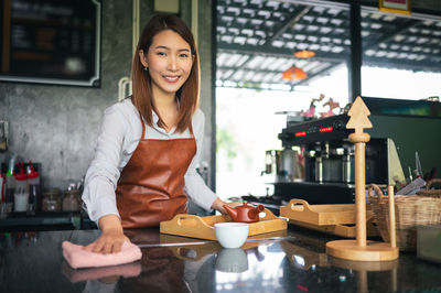 Portrait of smiling female owner working at checkout in cafe