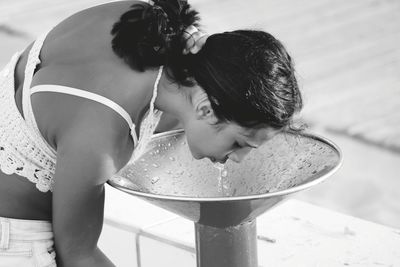 Side view of young woman drinking water from fountain