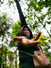 Low angle view of woman wearing mask standing in forest