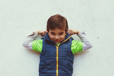 Portrait of smiling boy standing against wall