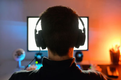 Rear view of man using mobile phone at home