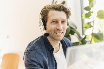 Smiling mid adult man wearing headphone sitting at home