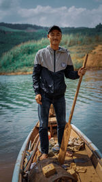 Portrait of young man standing on lake