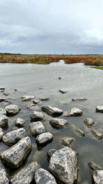 Stones on beach against sky