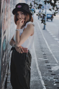 Portrait of woman standing on sidewalk in city