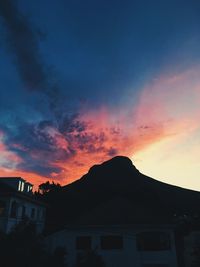 Silhouette houses against sky during sunset