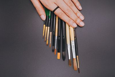 Close-up of hand holding pencils against white background