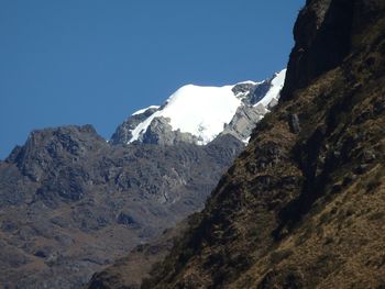 Low angle view of rocky mountains against blue sky