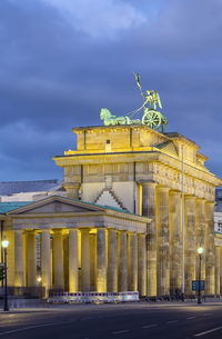 Statue in city against cloudy sky