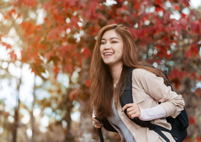 Portrait of young woman standing against trees