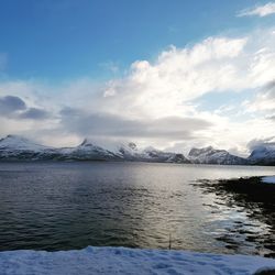 Scenic view of lake by snowcapped mountains against sky