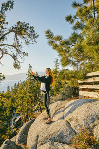 Young woman taking a picture of sunset over lake tahoe.