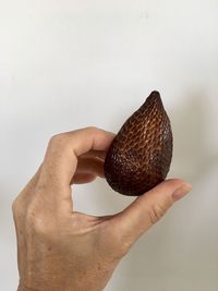 Close-up of hand holding strawberry over white background