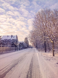 Road by snow covered city against sky