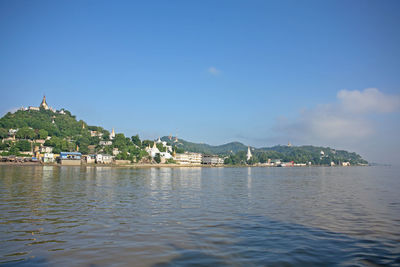 Scenic view of sea by city buildings against sky
