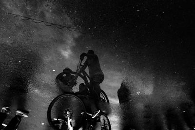 Silhouette of man riding bicycle on road at night