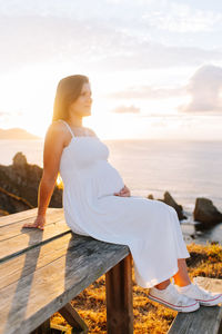 Woman sitting on shore against sky