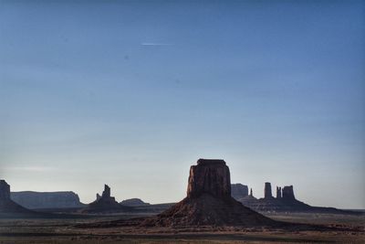 Rock formations on landscape against clear blue sky