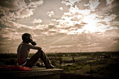 Man sitting on landscape against sky