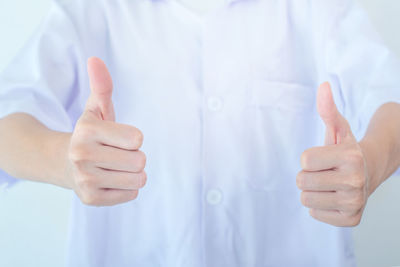 Midsection of female doctor gesturing against wall