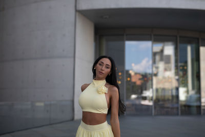 Portrait of young woman standing against wall