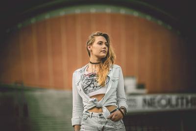 Portrait of young woman looking away while standing outdoors