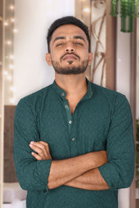 Portrait of young man standing against window