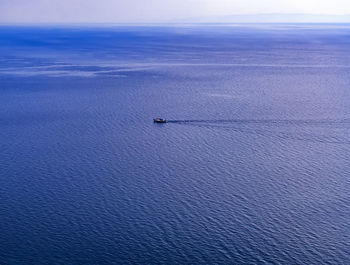 View of a horizon with a small ship over the large body of water. panoramic blue waterscape.