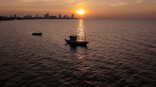 Silhouette boat in sea against sky during sunset