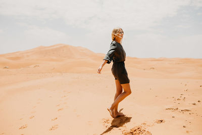 Woman walking on desert in sunny day