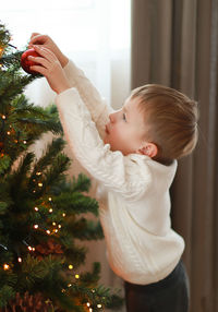 Side view of boy with christmas tree at home