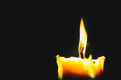 Close-up of burning candle against black background