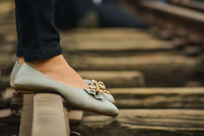 Low section view of woman standing on wooden railway track