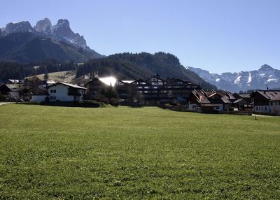 Houses on field by mountains against clear sky