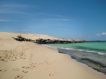 Scenic view of beach against blue sky