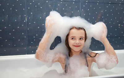 Girl smiling while bathing in bathtub