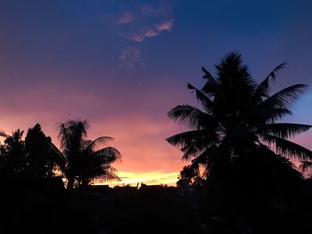 Silhouette palm trees against romantic sky at sunset
