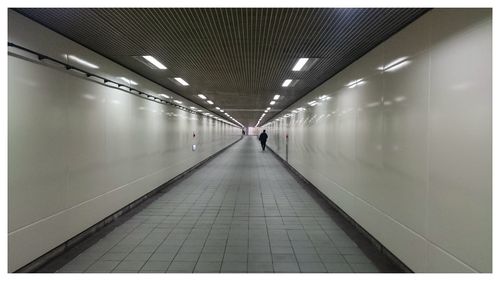 Rear view of man walking in illuminated subway