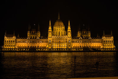 Illuminated hungarian parliament building by river in city at night