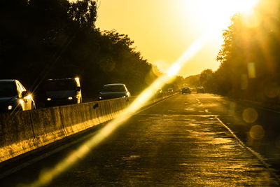 Cars on road against sky during sunset