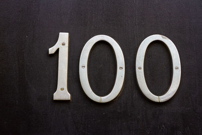 House number 100 on a dark wooden front door in london 