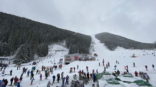 Group of people on snowy mountain against sky