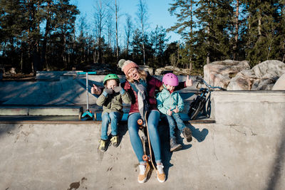 Mom and her kids playing at a skate park with scooters and bikes